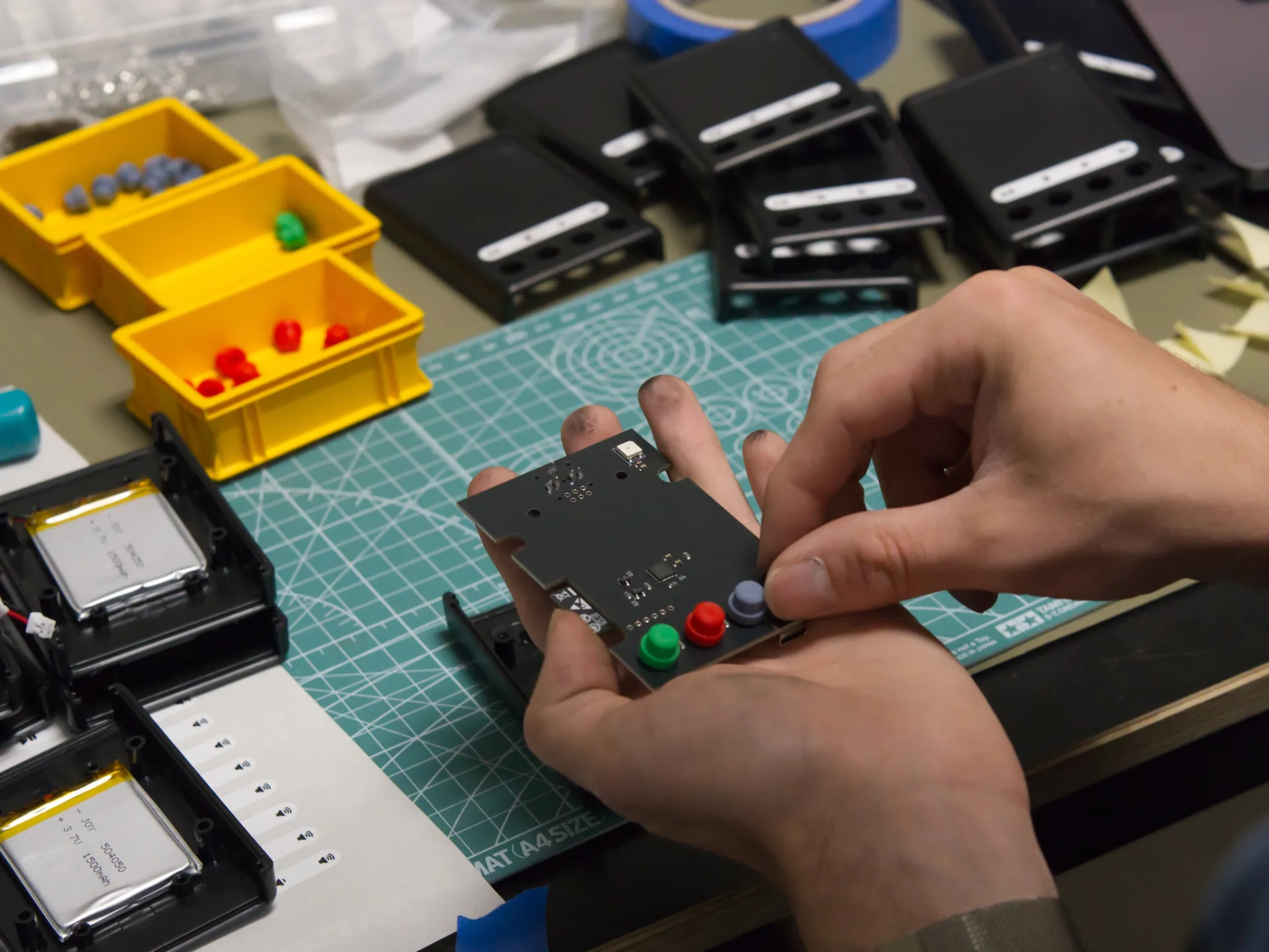 Der MP3-Player wird zusammengebaut. Jemand montiert die Kunststoff-Knöpfe.