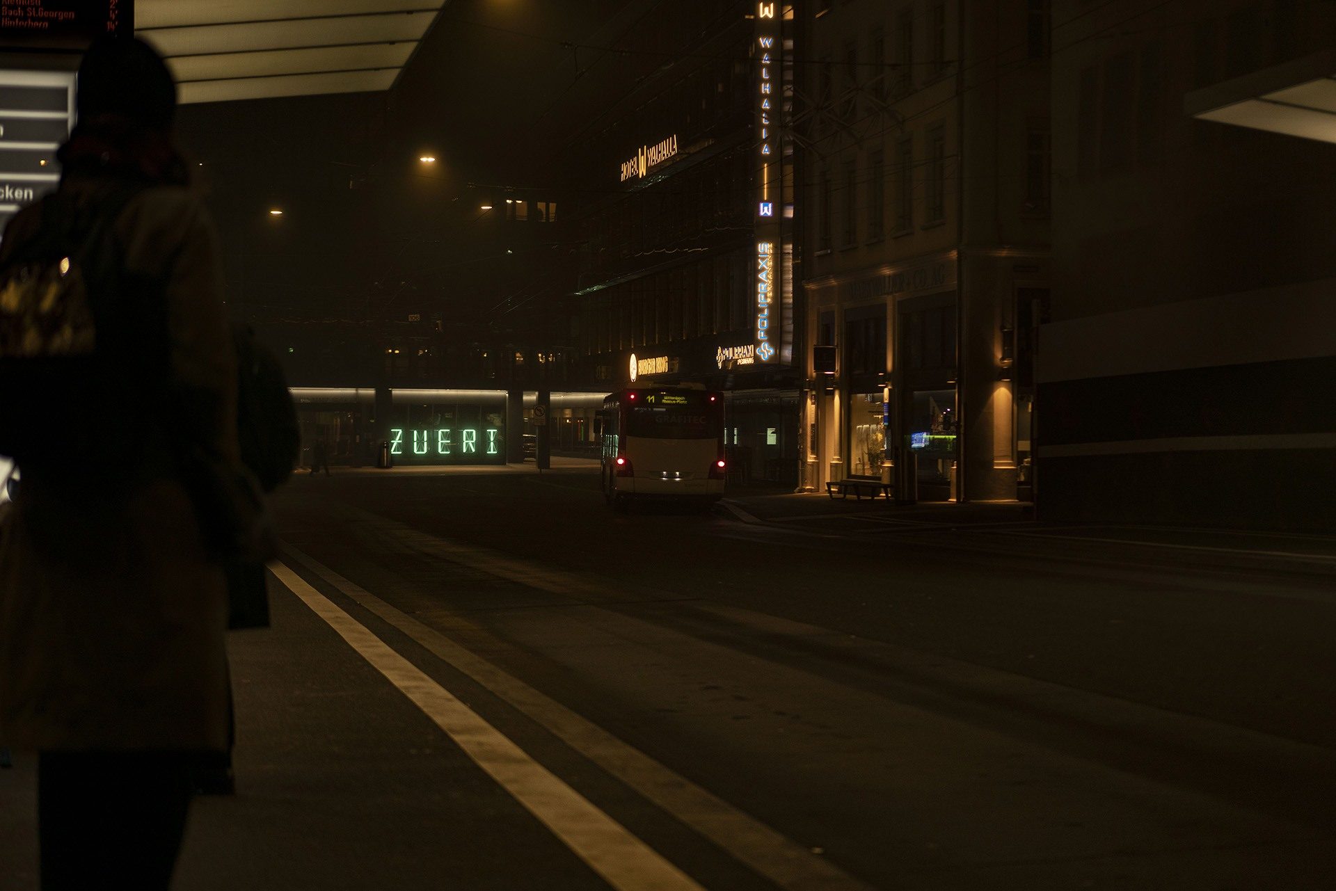 Aufnahme von einer Strasse in Richtung des Bahnhof St. Gallen. Die Lichtinstallation 5x14 zeigt in leuchtenden Buchstaben das Wort «ZUERI».