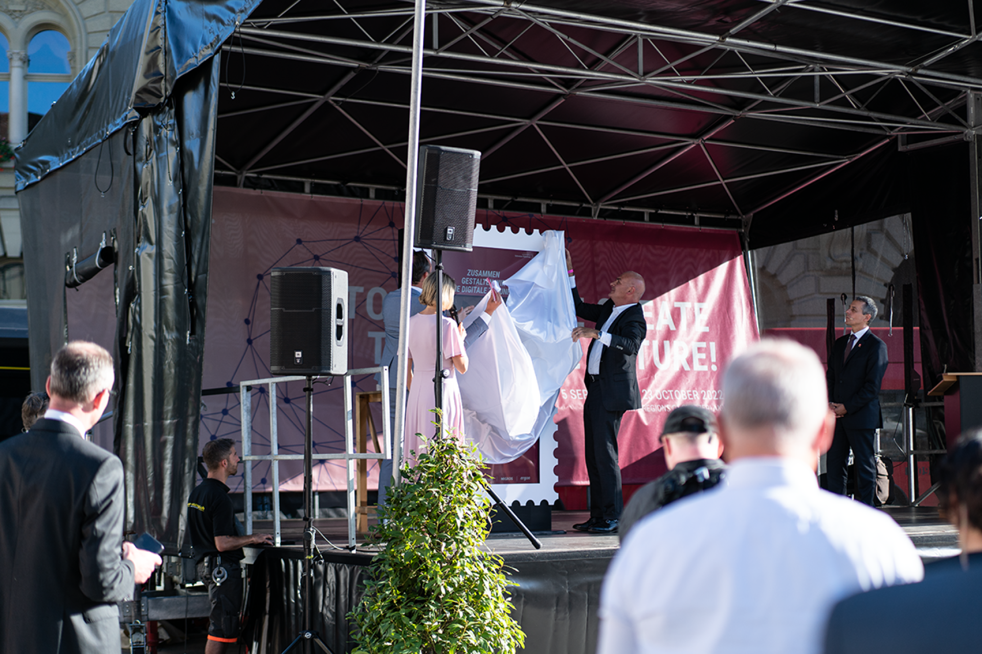 Ignazio Cassis schaut zu, wie die Stele auf einer Bühne enthüllt wird