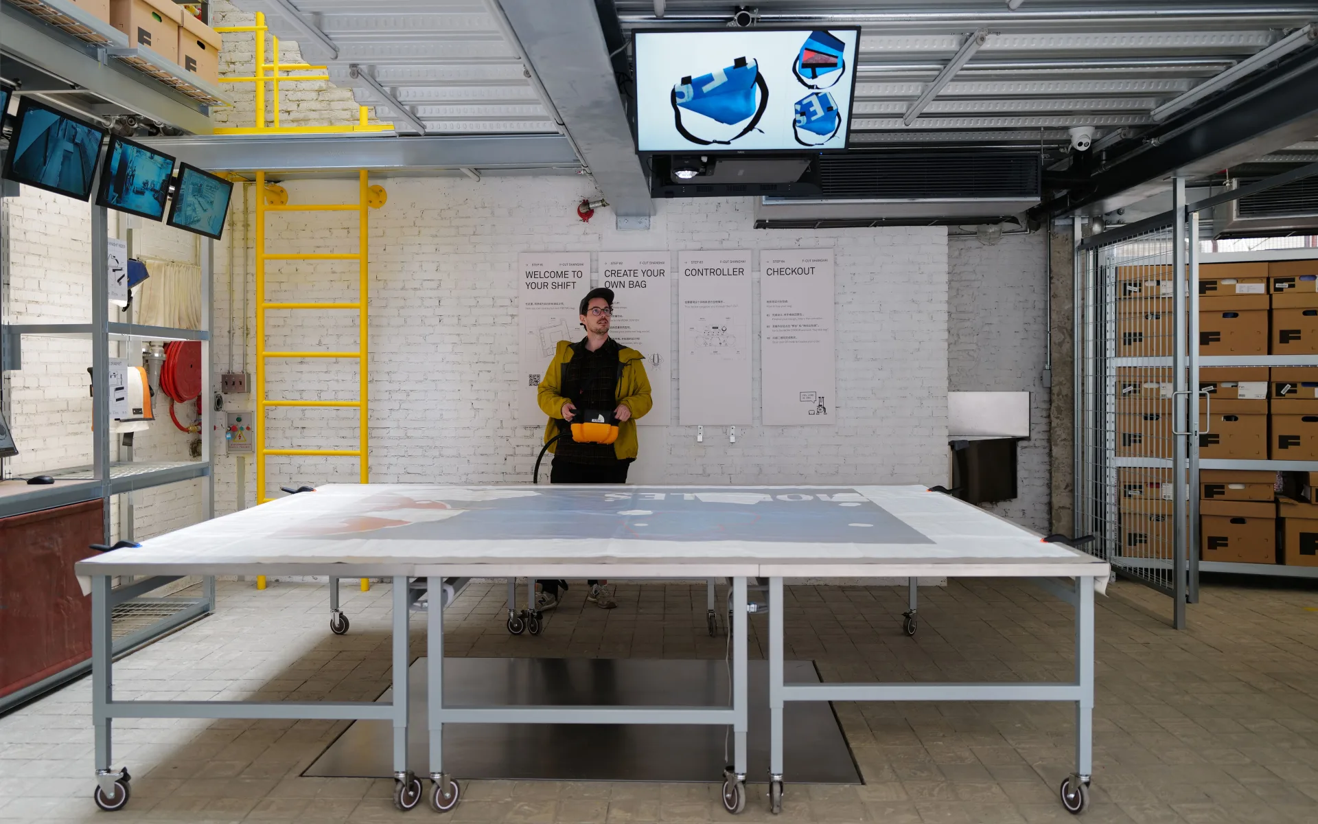 Sicht auf die Installation, bestehend aus einem grossen Tisch, auf den mittels einem Projektor an der Decke Planen projiziert werden.