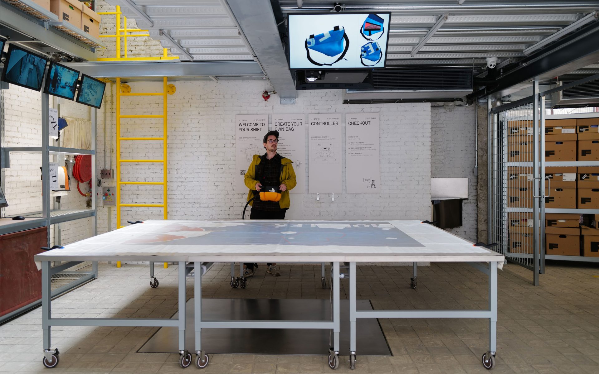 Sicht auf die Installation, bestehend aus einem grossen Tisch, auf den mittels einem Projektor an der Decke Planen projiziert werden.