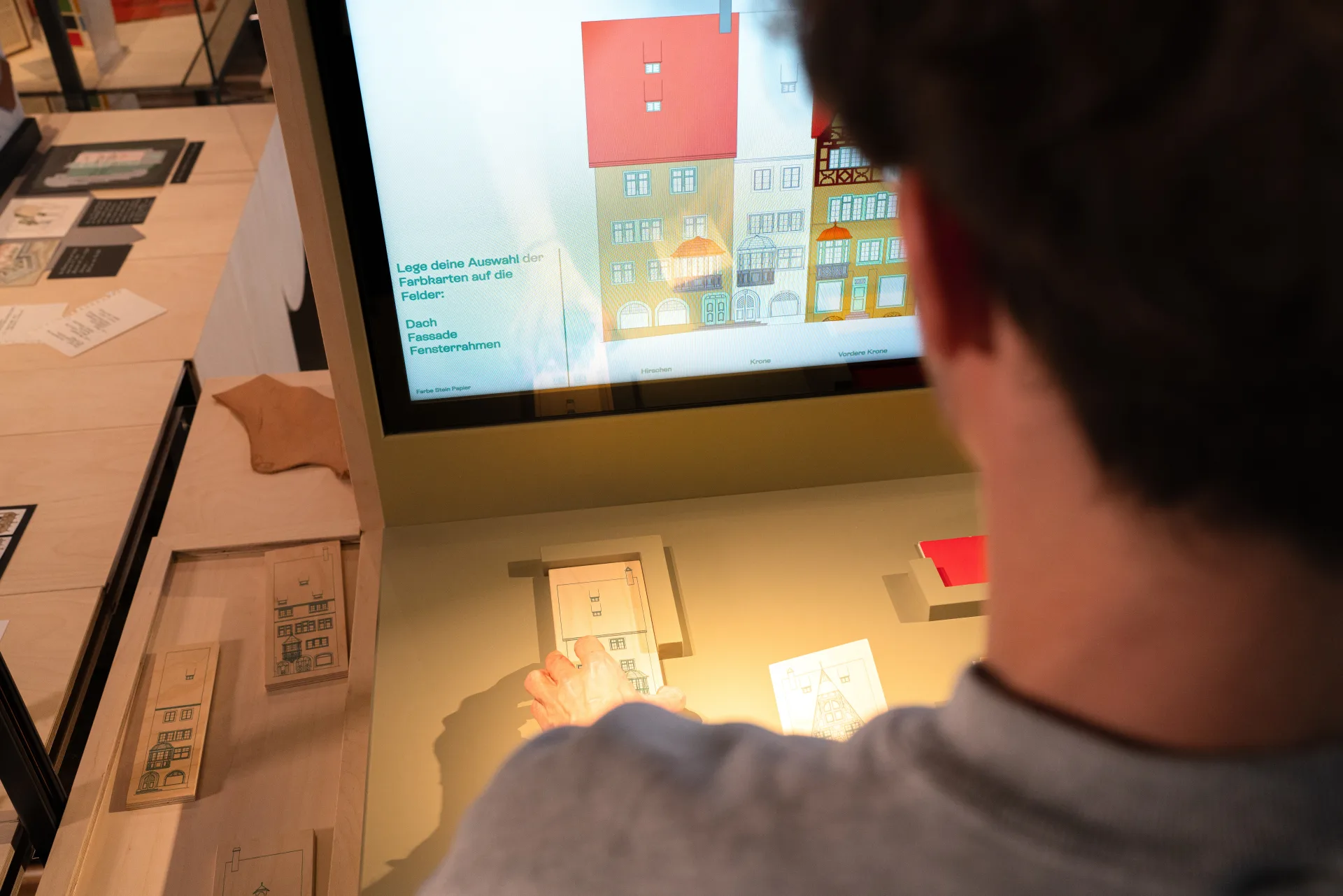 Eine Person legt eine Hauskarte auf den Sensor.