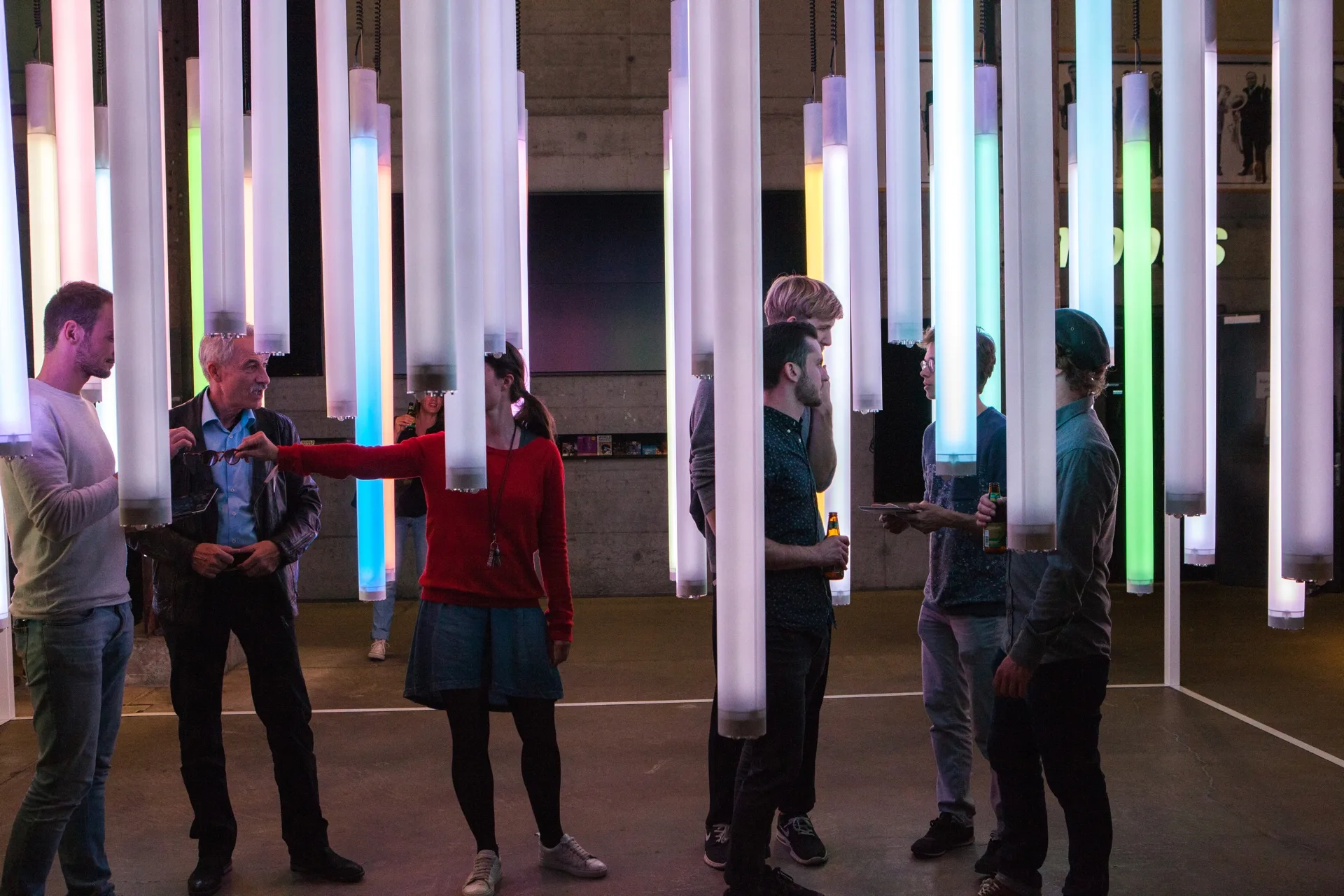 Verschiedene Personen stehen in der farbigen Lichtinstallation