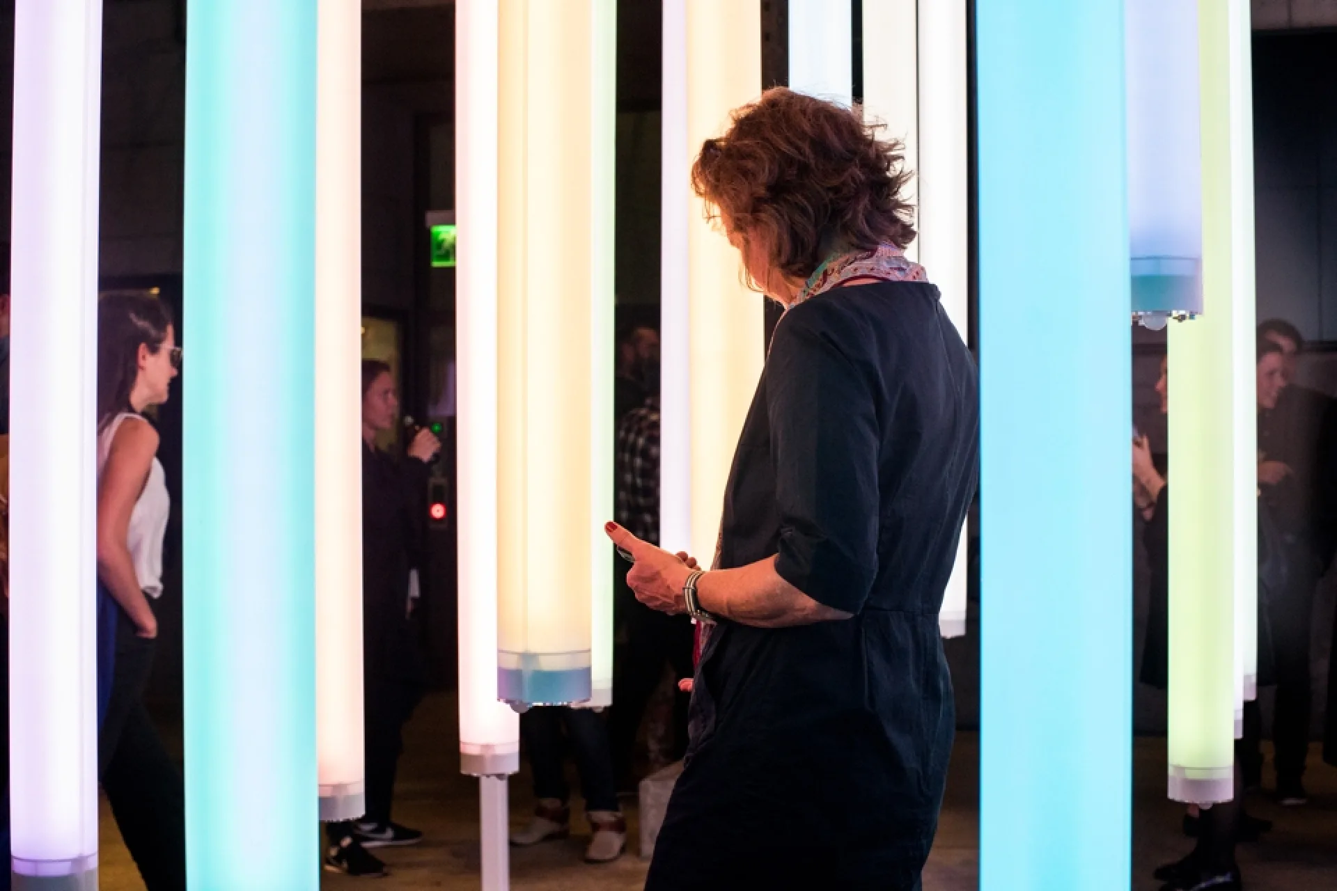 Besucherin zwischen den farbingen Lichtröhren