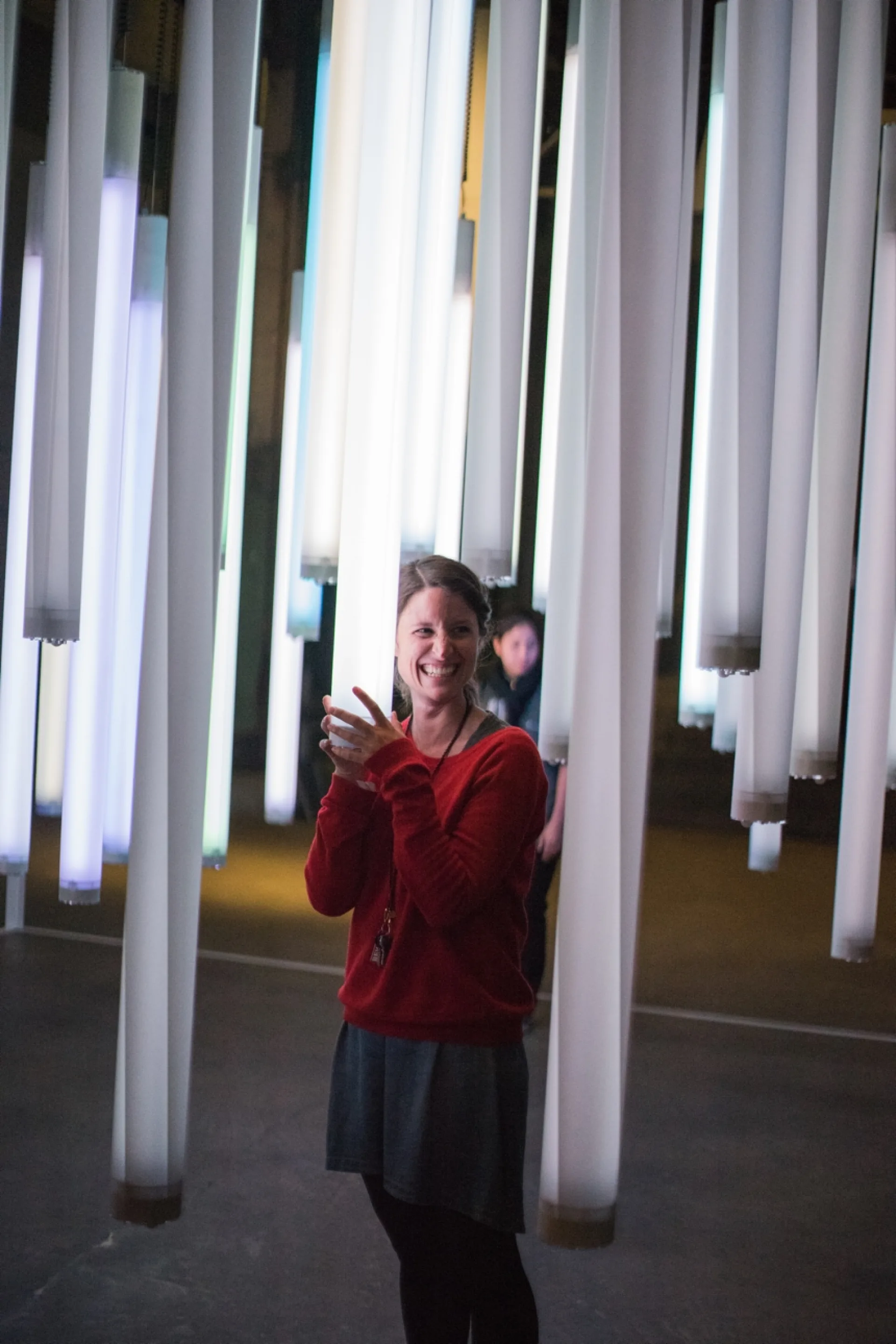 Mona hält eine Lichtröhre und lacht.