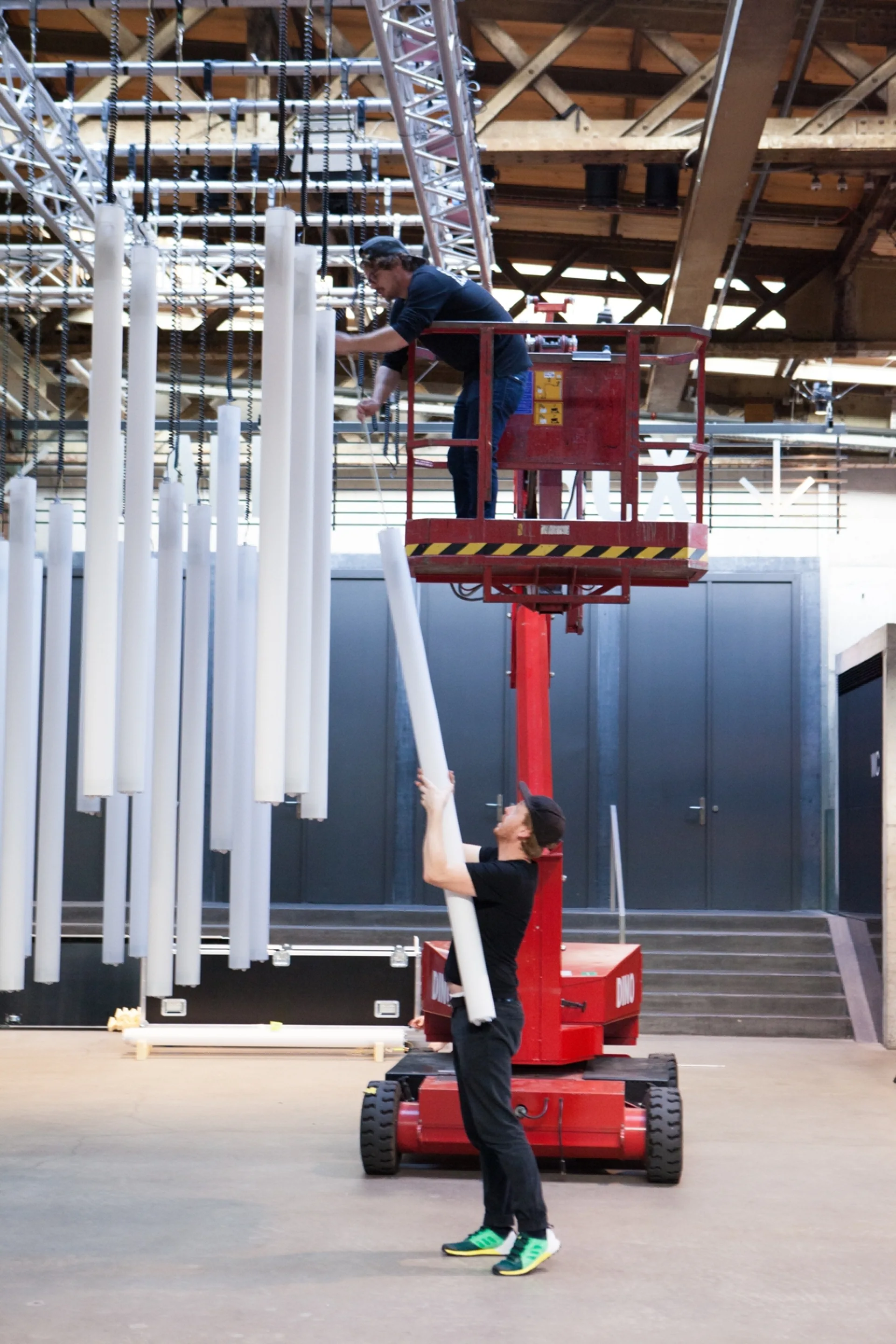 Zwei Personen hängen eine Lichtröhre auf