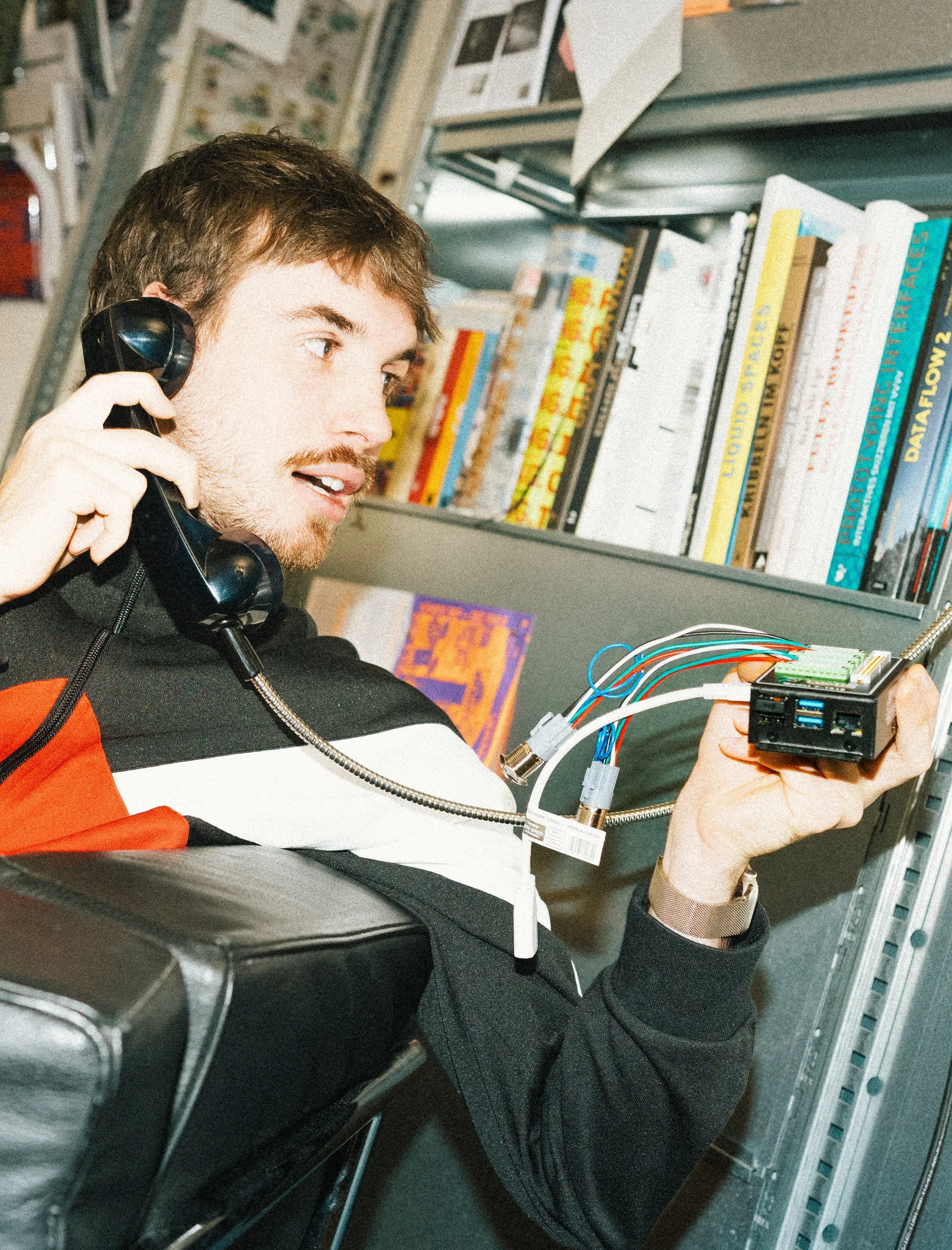 Dario ist am Telefon und hält Elektronik-Komponenten in der Hand.